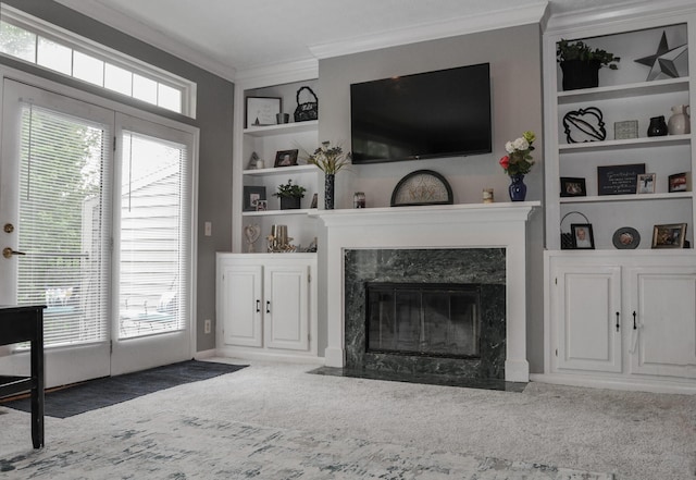 carpeted living area featuring crown molding, a high end fireplace, and built in shelves