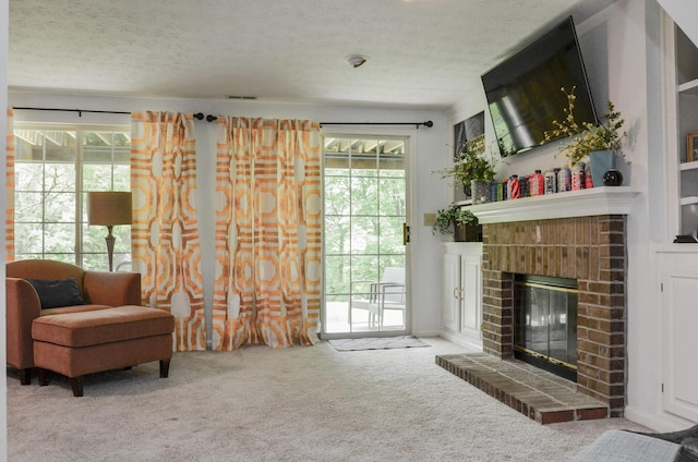 sitting room with carpet, a fireplace, plenty of natural light, and a textured ceiling