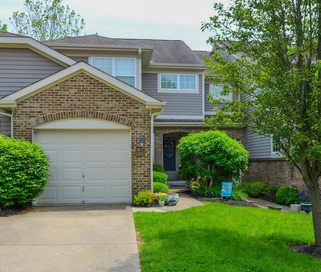 view of front facade with driveway, a front yard, brick siding, and an attached garage
