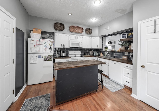 kitchen with white appliances, wooden counters, a sink, white cabinets, and light wood-style floors