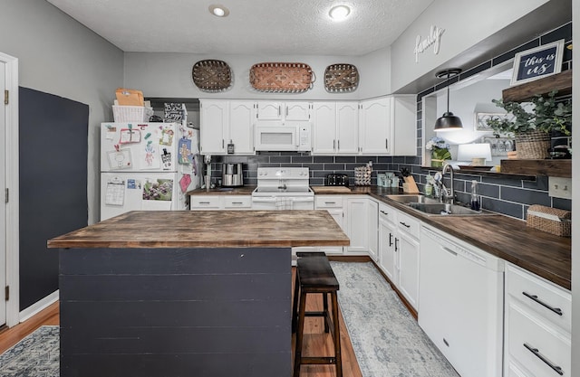 kitchen with butcher block countertops, white appliances, a sink, and a textured ceiling