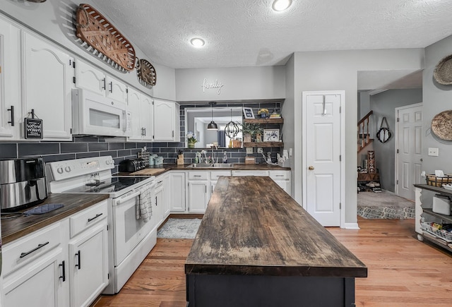 kitchen featuring white appliances, wood counters, a center island, a sink, and a textured ceiling