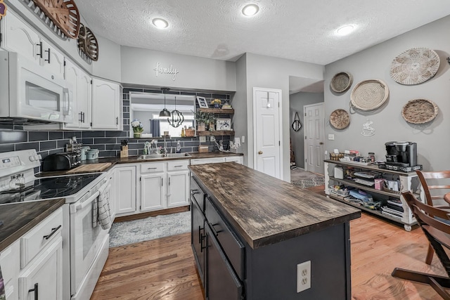 kitchen featuring white appliances, butcher block countertops, open shelves, a textured ceiling, and white cabinets