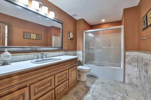 9015 Washington Trace Rd, California, KY 41007 - full bathroom with tile walls, vanity, combined bath / shower with glass door, stone finish floors, and wainscoting