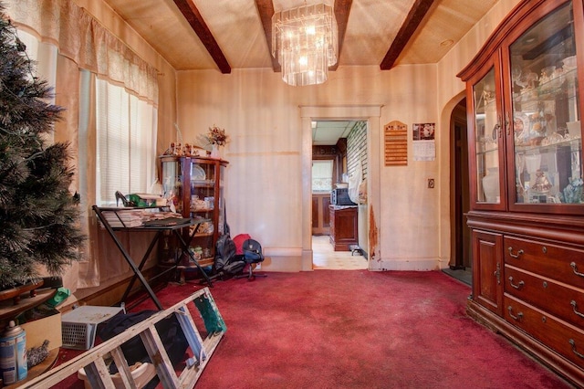 misc room featuring beamed ceiling, carpet flooring, a chandelier, and arched walkways