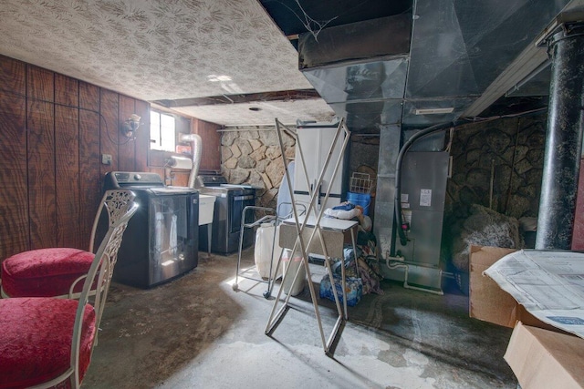 below grade area featuring heating unit, washing machine and dryer, wood walls, and a textured ceiling