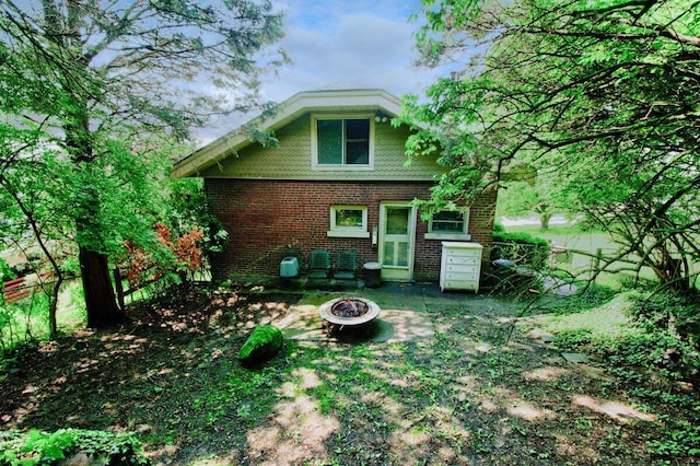back of property with brick siding and a fire pit