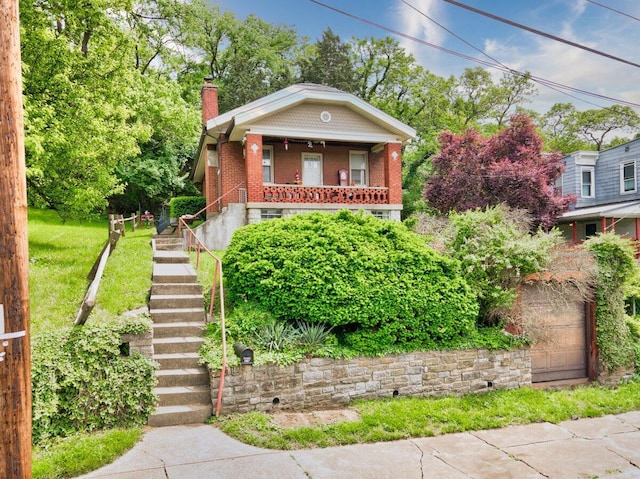 bungalow-style house featuring stairs, a chimney, covered porch, and brick siding