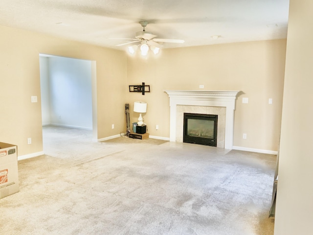 unfurnished living room featuring a ceiling fan, a tile fireplace, carpet, and baseboards
