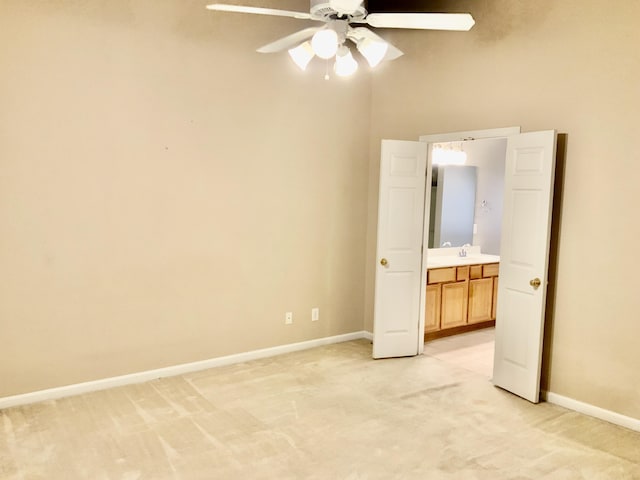 unfurnished bedroom featuring light carpet, baseboards, connected bathroom, and a ceiling fan
