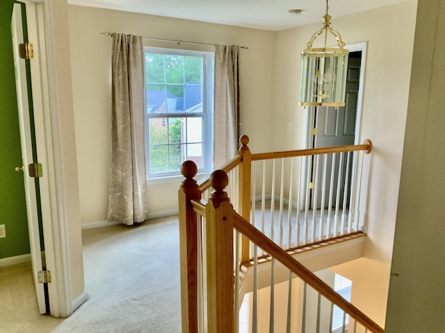 hall featuring an upstairs landing, carpet flooring, and baseboards