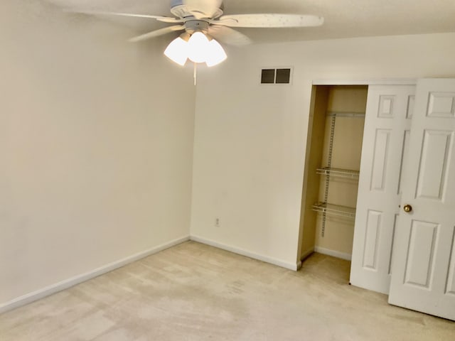 unfurnished bedroom featuring light carpet, a closet, baseboards, and a ceiling fan