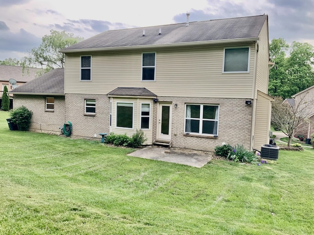back of house featuring brick siding, a lawn, a patio, and cooling unit