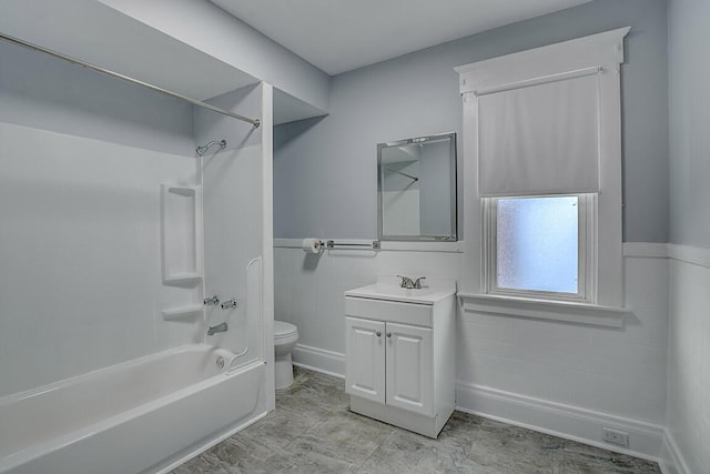 full bath with toilet, washtub / shower combination, vanity, and a wainscoted wall