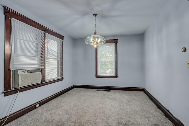 carpeted empty room with a chandelier, baseboards, and cooling unit