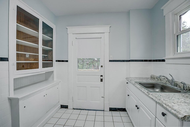 laundry room with a sink, light tile patterned flooring, tile walls, and wainscoting