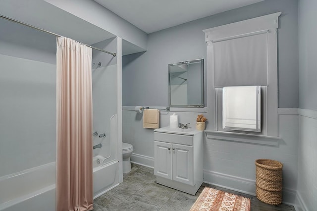 full bathroom with shower / tub combo with curtain, toilet, vanity, and a wainscoted wall