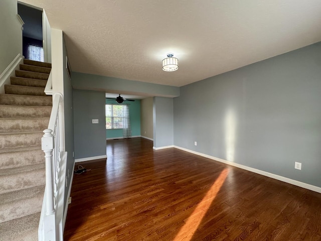 unfurnished room with wood finished floors, stairway, a ceiling fan, and baseboards