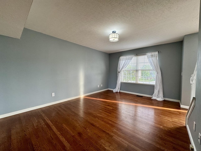 unfurnished room featuring wood finished floors, a textured ceiling, and baseboards