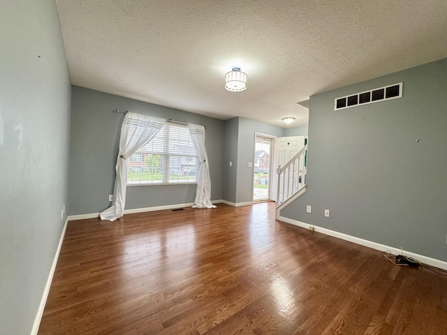 spare room featuring wood finished floors, a textured ceiling, stairway, and baseboards