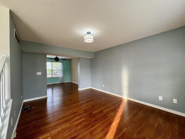 empty room with wood finished floors, a ceiling fan, baseboards, and a textured ceiling