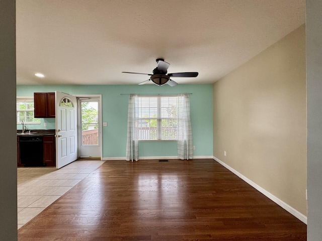 unfurnished living room with a ceiling fan, light wood finished floors, and baseboards