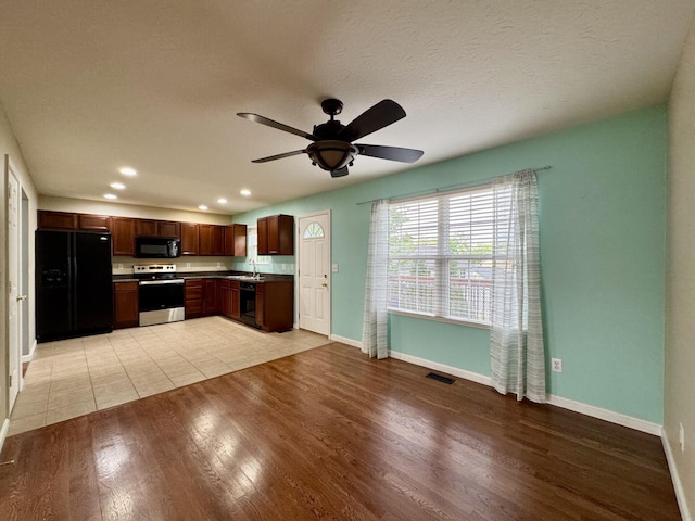 kitchen featuring black appliances, a sink, baseboards, light wood-style floors, and recessed lighting