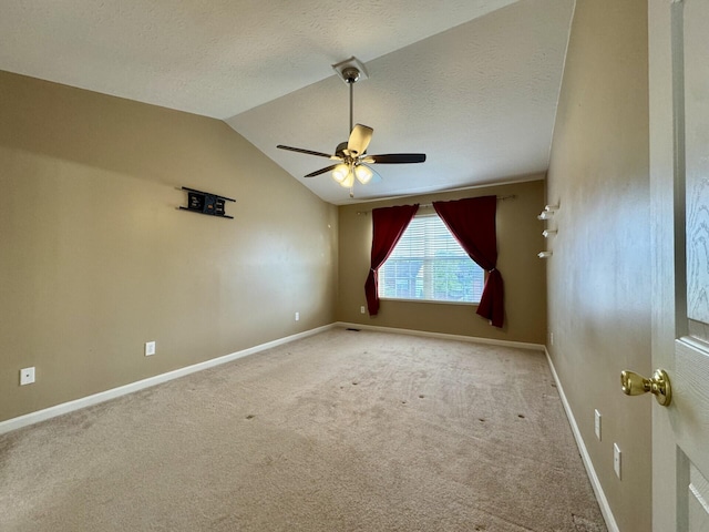 spare room with lofted ceiling, ceiling fan, carpet floors, baseboards, and a textured ceiling