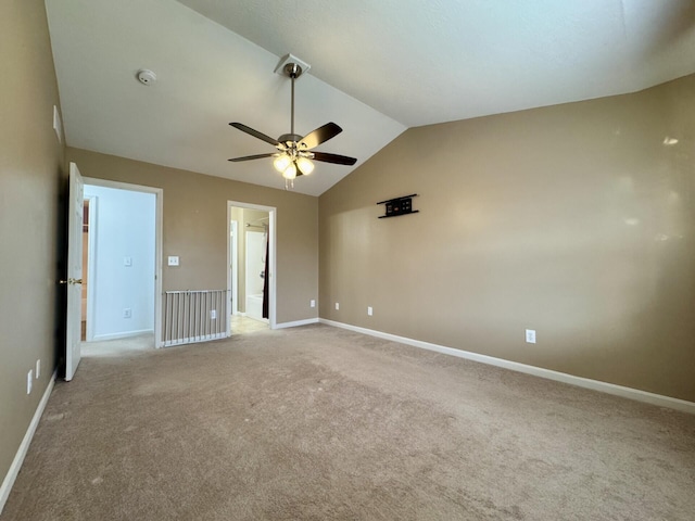 unfurnished room with a ceiling fan, vaulted ceiling, light colored carpet, and baseboards