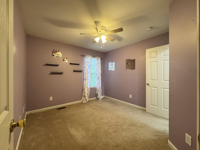carpeted empty room with a ceiling fan, a textured ceiling, a smoke detector, and baseboards