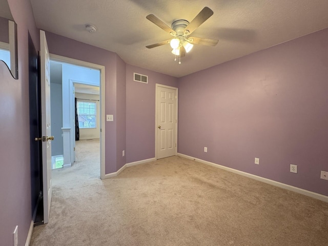 unfurnished bedroom with light carpet, baseboards, ceiling fan, and a textured ceiling