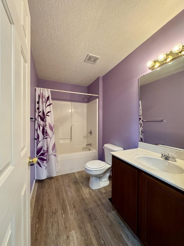 full bath featuring wood finished floors, toilet, vanity, a textured ceiling, and shower / bathtub combination with curtain