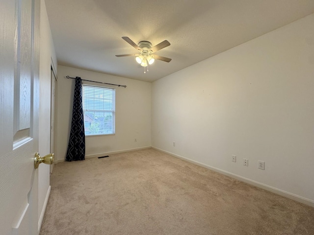 carpeted spare room featuring ceiling fan and baseboards