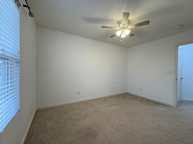 carpeted spare room with ceiling fan and baseboards