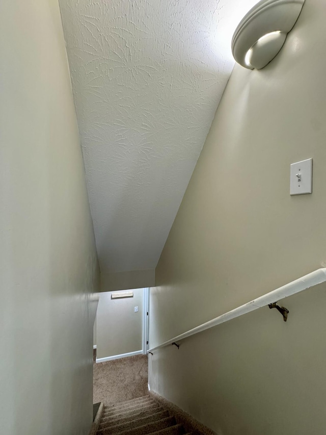 staircase with carpet, lofted ceiling, and baseboards
