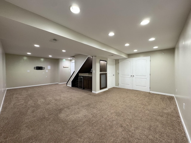 finished below grade area with light colored carpet, baseboards, recessed lighting, and stairs