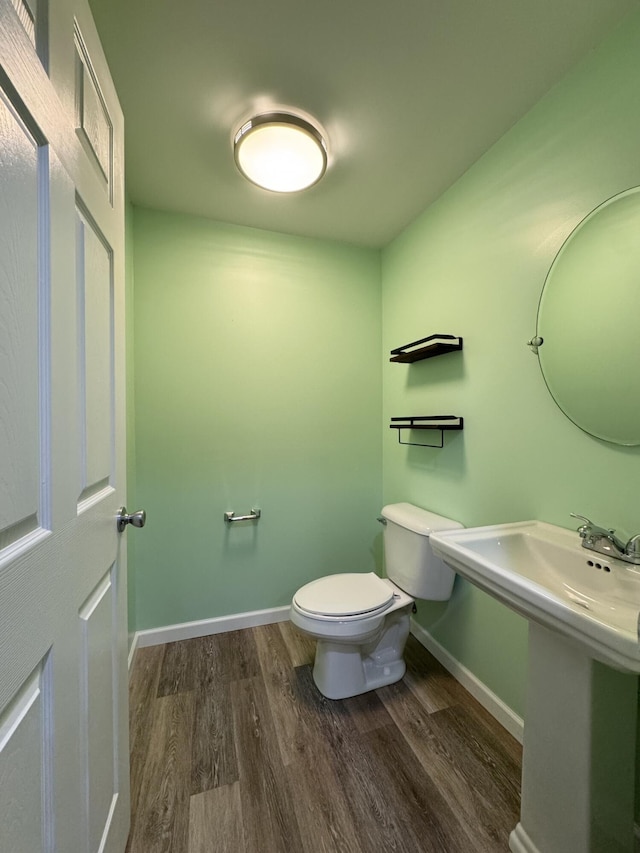 half bath with wood finished floors, toilet, and baseboards