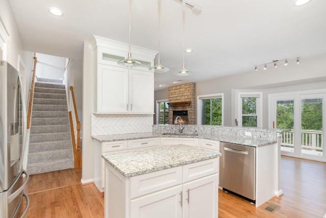 1169 Appomattox Dr, Florence, KY 41042 - kitchen featuring appliances with stainless steel finishes, a peninsula, a sink, light wood finished floors, and white cabinets