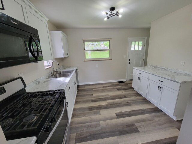 3157 Woodward St, Erlanger, KY 41018 - kitchen featuring stainless steel gas range oven, black microwave, a sink, light wood finished floors, and white cabinets