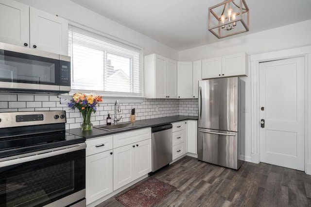 2730 Dakota Ave, Covington, KY 41015 - kitchen featuring stainless steel appliances, a sink, dark countertops, and a chandelier