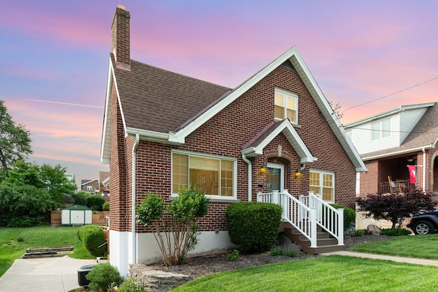 view of front of house featuring brick siding, a shed, a chimney, and an outdoor structure