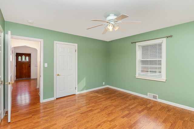 empty room with light wood-style floors, a ceiling fan, baseboards, and a smoke detector