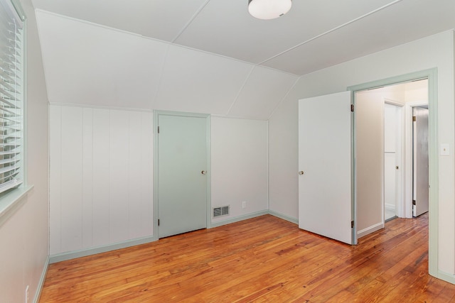additional living space with light wood-style floors and lofted ceiling