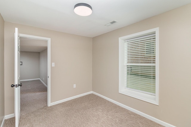 unfurnished room featuring light carpet and baseboards