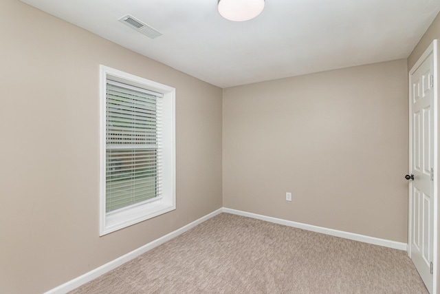 spare room with baseboards and light colored carpet