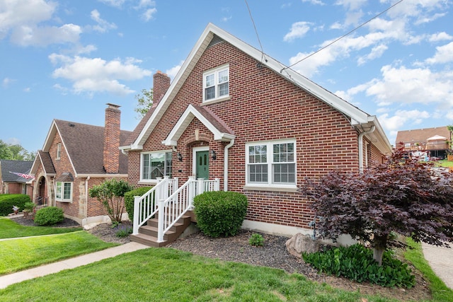 view of front of property with brick siding, a chimney, and a front lawn
