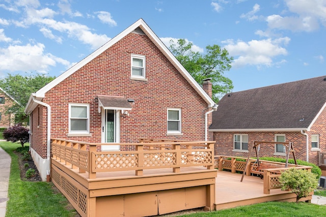 rear view of house featuring brick siding, a wooden deck, and a chimney