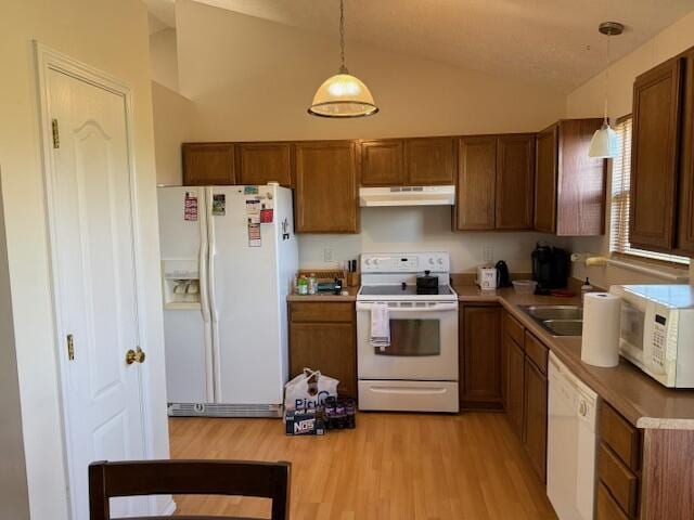 kitchen featuring white appliances, under cabinet range hood, lofted ceiling, pendant lighting, and light wood-style flooring