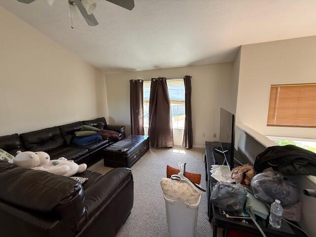 carpeted living area with a ceiling fan