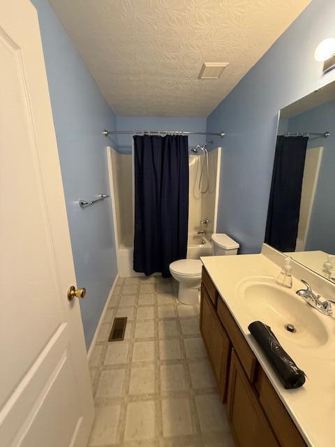 bathroom with shower / bath combination with curtain, a textured ceiling, toilet, vanity, and tile patterned floors